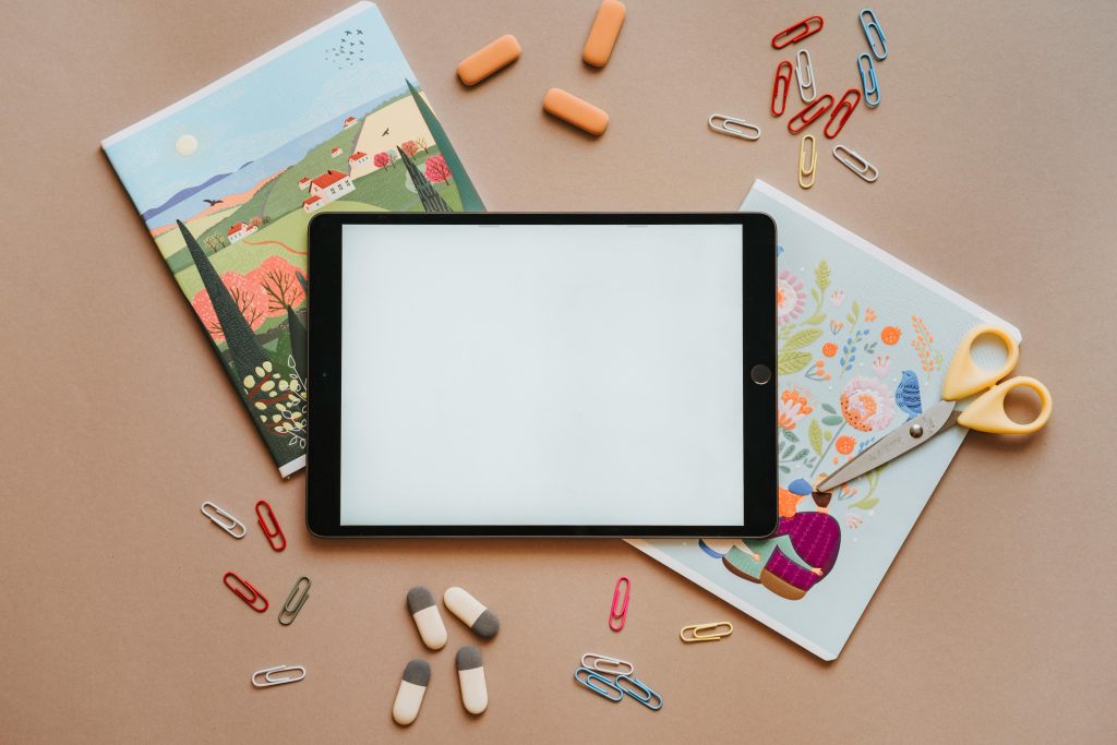 Et foto i fugleperspektiv av en iPad med ulike skolesaker rundt